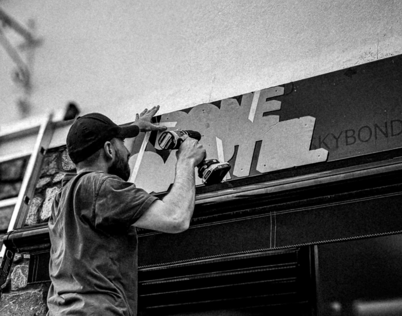 Fixing a rigid panel to a fascia above a shopfront
